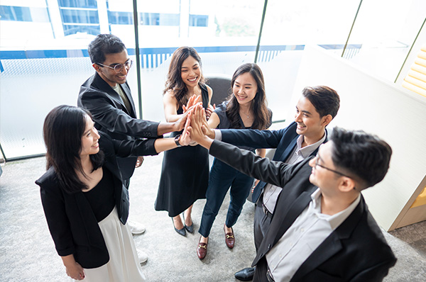 Young professionals in business attire giving a high-five in a bright office space.